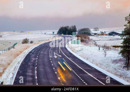 Tebay, Cumbria, Royaume-Uni. 15 Décembre, 2019. Des teintes subtiles à l'aube ; tôt le matin de givre et de neige couvrant la Tebay paysage d'hiver comme chefs de trafic d'un Shap célèbre spot de conduite difficile à froid dans les Fells Westmorland. Credit : MediaWorldImages/Alamy Live News Banque D'Images