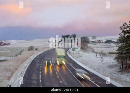 Tebay, Cumbria, Royaume-Uni. 15 Décembre, 2019. Des teintes subtiles à l'aube ; tôt le matin de givre et de neige couvrant la Tebay paysage d'hiver comme chefs de trafic d'un Shap célèbre spot de conduite difficile à froid dans les Fells Westmorland. Credit : MediaWorldImages/Alamy Live News Banque D'Images