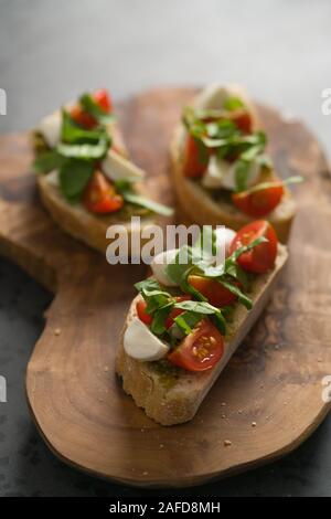 La bruschetta avec de la mozzarella, tomates cerises et pesto sur conseil d'olive, l'accent peu profondes Banque D'Images