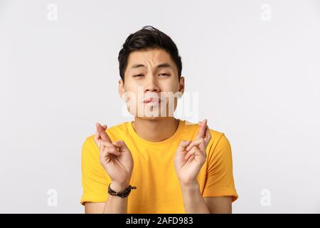 Veuillez le faire se produire. Jeune Espoir asian man in yellow t-shirt, les doigts bonne chance, faisant acte de visage ont grand désir ou rêve, tiens tiens Banque D'Images