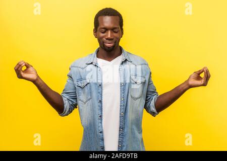 L'équilibre et l'harmonie. Portrait d'un homme pacifique en denim chemise décontractée avec manches roulées dans les griffes de mudra geste, méditant avec Banque D'Images