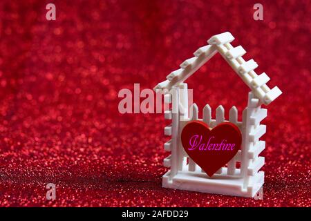 Petite maison blanche et rouge coeur écrit avec les mots "Happy Valentine's Day ' sur le fond rouge pour votre modèle de conception ou votre valentin concept. Banque D'Images