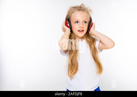 Sports adolescentes dans le sport à faire écouter de la musique avec de grands écouteurs isolé sur fond rouge Banque D'Images