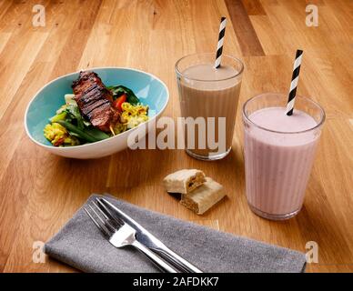 Plan de repas quotidien contrôlé en calories, y compris le petit-déjeuner, un snack et milkshake repas du soir de délicieux poulet, tourné sur un fond de bois Banque D'Images