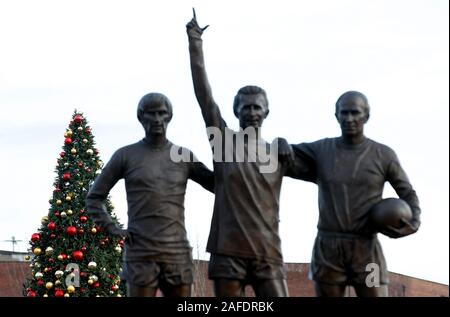 Une vue de l'arbre de Noël est vu derrière la statue de Manchester United's "Sainte Trinité" de Sir Bobby Charlton, George Best et Denis Law à l'extérieur du terrain avant le premier match de championnat à Old Trafford, Manchester. Banque D'Images