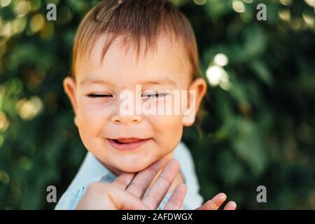 Happy Baby avec les yeux fermés et les mères part touchant le menton. Vie Banque D'Images