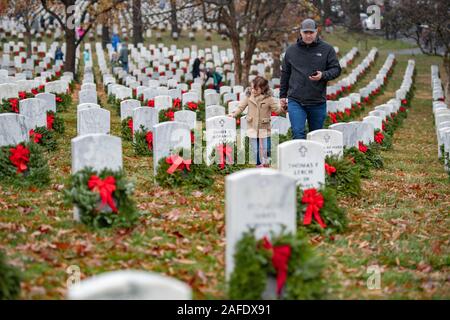 Arlington, États-Unis d'Amérique. 14 Décembre, 2019. Les membres de la famille passent devant les tombes de membres de service marquée par des couronnes au cours de la 28e Journée de l'Amérique à travers des couronnes au cimetière national d'Arlington, le 14 décembre 2019 à Arlington, en Virginie. Plus de 38 000 couronnes au lieu des bénévoles chaque tombe au cimetière national d'Arlington et autres sites autour de la nation. Credit : Elizabeth Fraser/DOD/Alamy Live News Banque D'Images