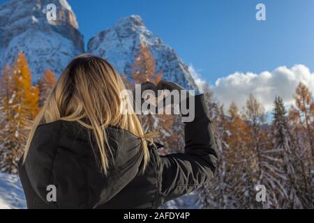 Fille blonde vu de derrière l'élaboration d'un cœur avec ses mains Banque D'Images