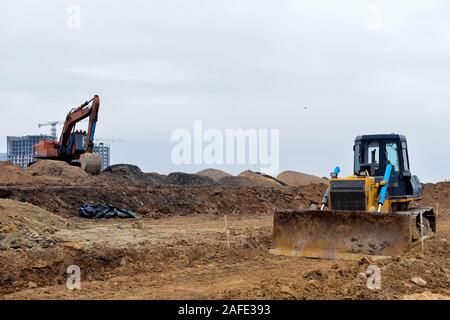 Pelle et d'un bulldozer qui travaillent sur un chantier de construction. Le défrichement des terres, le nivellement, l'excavation de bassin, de tranchées et de l'utilitaire foundation creuser. Pose d'u Banque D'Images