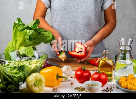 Femme nettoie les poivrons, salade de cuisson dans la cuisine. Régime alimentaire sain concept. Banque D'Images