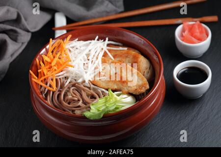 Partie de la soupe aux nouilles soba avec des tranches de poulet frit, du radis daikon, carotte, gingembre mariné, et feuilles de bok choy Banque D'Images