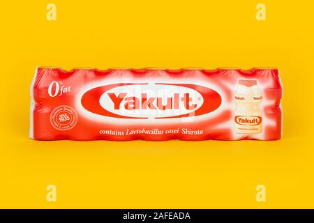 Un pack de 7 LAIT PROBIOTIQUE Yakult les bouteilles de boissons sucrées tourné sur un fond jaune. Banque D'Images