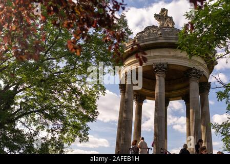 Paris, France - 16 juin 2017 : Les Visiteurs du temple de la Sibylle au Parc des Buttes Chaumont vu à travers les branches d'arbres, pris sur un début de l'été un soleil Banque D'Images