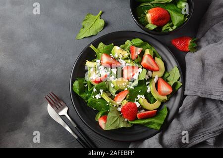 Salade de fraises d'été avec épinards, fromage feta, avocat, vinaigre balsamique et huile d'olive dans une assiette. Nourriture végétalienne. Concept d'alimentation saine Banque D'Images