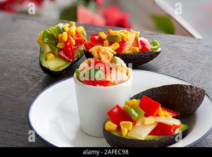 Avocats farcis aux légumes et des œufs brouillés et des pommes en bois sur un paysage flou et la lumière d'arrière-plan Banque D'Images