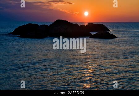 Avril rouge-sang coucher de soleil dans l'océan à l'ouest de l'île de l'oin Kirkehamn Hidra dans le sud-ouest de la Norvège. Banque D'Images