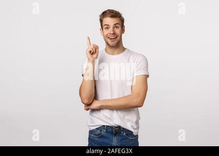 Qu'il entende, excellente idée. moi débranchées Happy attractive smiling blonde gars en t-shirt blanc, lever l'index eureka geste et grimaçantes, ajouter Banque D'Images