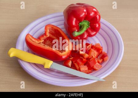 Ensemble, la moitié des morceaux de poivron rouge avec un couteau sur une plaque Banque D'Images