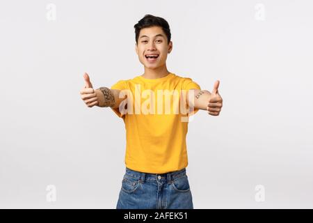 Bon travail, votre porte très bien. Cheerful handsome asian male ami vous encourage à aller, showing thumbs-up dans l'approbation, comme produit, à recommander Banque D'Images