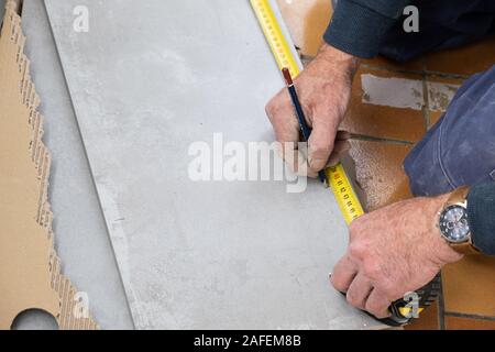 Le carreleur mesure les carreaux avant qu'elle coupe Banque D'Images