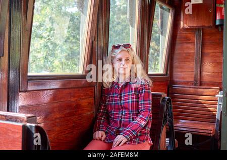 Une femme vêtue de rouge chemise tartan Royal Stewart assis dans un train vintage Banque D'Images