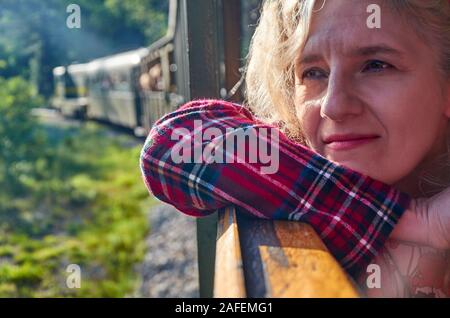 Femme à la fenêtre d'un train et regarder dehors tout en voyageant Banque D'Images