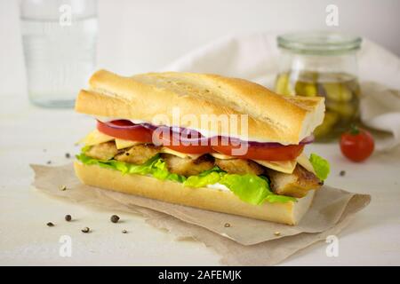 La photographie culinaire d'un sandwich au poulet grillé avec sauce tomate et oignon rouge sur une baguette de pain. Banque D'Images