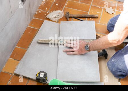 Le carreleur mesure les carreaux avant qu'elle coupe Banque D'Images