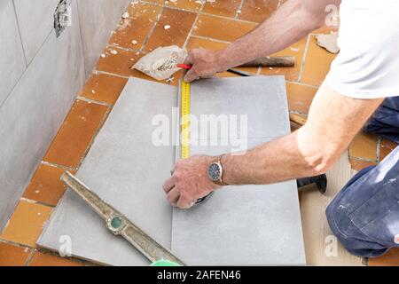 Le carreleur mesure les carreaux avant qu'elle coupe Banque D'Images