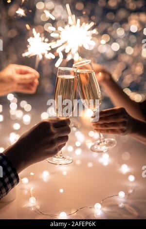 Mains de friends holding flutes de champagne et feux de Bengale mousseux Banque D'Images