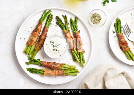 Tasty bacon enveloppé les asperges sur plaque blanche sur fond noir en lumière. Haut de la vue, télévision lay Banque D'Images