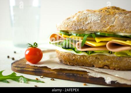 La photographie culinaire d'un sandwich au jambon et au fromage avec concombres sur un pain ciabatta de blé entier Banque D'Images