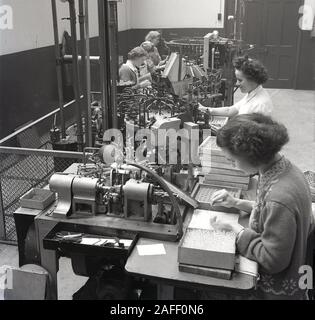 Années 1950, historiques, les ouvrières d'usine utilisant des machines de l'époque dans la production d'ampoules, Angleterre, Royaume-Uni. Banque D'Images