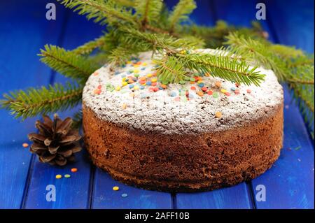 Gâteau aux fruits de Noël au chocolat recouvert de sucre glace, fur le brunch et cône sur la table bleu closeup Banque D'Images