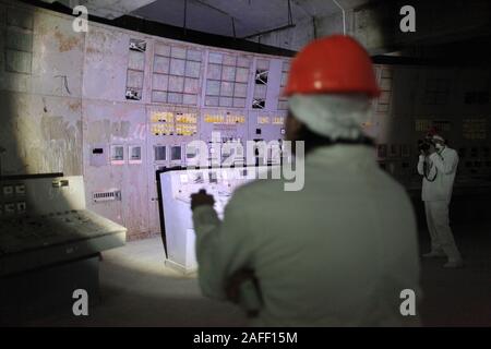 Les touristes qui visitent la salle de contrôle du réacteur de Tchernobyl, quatre le site de l'économie la plus terrible catastrophe nucléaire. L'ancienne centrale électrique nucléaire est la salle de contrôle où les ingénieurs fermer les pompes de refroidissement du réacteur dans le cadre d'un test de sécurité en avril 1986, qui a conduit à une explosion qui a tué au moins 28 personnes dans la suite immédiate et contaminé les environs. La chambre, située sous une tonne de confinement en acier 36 000-arch, a encore ses écrans et panneaux d'affichage d'origine de boutons de commande. Tchernobyl, Ivankiv, Kiev Kiev oblast, Ukraine, Europe Banque D'Images