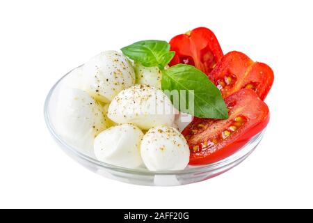 Salade Caprese isolé sur fond blanc. Mini boules de mozzarella au basilic et tomates cerises rouges dans un bol en verre. Une cuisine méditerranéenne. Banque D'Images