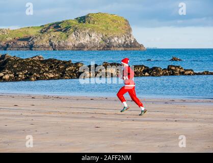 Man running in Santa run sur beach, North Berwick, East Lothian, Scotland, UK Banque D'Images