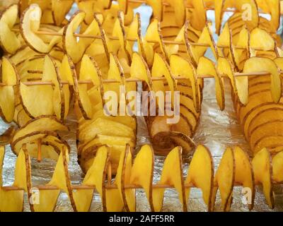 Une pile de rondelles de pommes de terre frites fines en spirale sur des bâtonnets de bois Banque D'Images