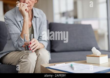 Portrait Portrait de pleurer senior woman holding glass of water assis sur la table tout en essayant de se calmer, copy space Banque D'Images