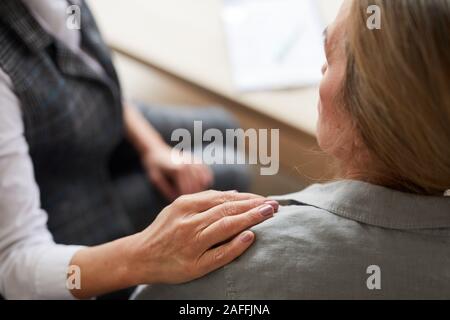 Gros plan du psychologue femelle portant la main sur l'épaule de senior patient tout en la réconfortant au cours de séance de thérapie, copy space Banque D'Images