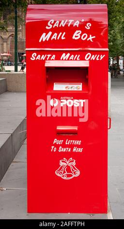 Melbourne, Australie - le 17 décembre 2009 : Le Père Noël rouge que boîte de rue. Les gens et le feuillage vert. Banque D'Images