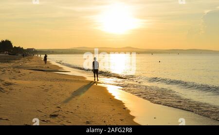 Un jeune homme marche sur beau lever de plage dans le sud du Vietnam. Banque D'Images