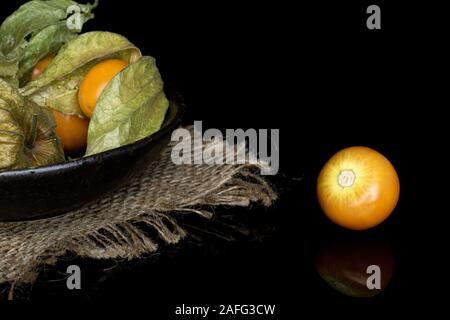 Beaucoup d'orange frais entier physalis avec tissu jute en vitrage isolé sur bol en verre noir Banque D'Images