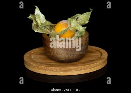 Un ensemble de fresh orange physalis dans bol bambou bambou ronde sur coaster isolé sur verre noir Banque D'Images