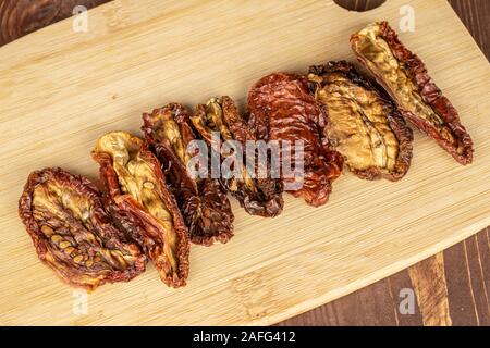 Groupe des sept pièce tomate rouge sèche entière sur une planche à découper en bambou bois brun sur flatlay Banque D'Images