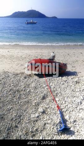 Bateau gonflable en caoutchouc rouge sur plage avec petit yacht amarré au large, l'île de Fitzroy, Grande Barrière de Corail, Queensland, Australie. Pas de PR Banque D'Images