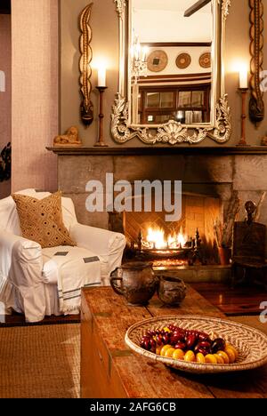 JUN 20, 2011 Serengeti, Tanzanie - Luxe African Safari Lodge intérieur avec des fauteuils blancs vintage table en bois sous une lumière chaude à partir de la cheminée avec Banque D'Images