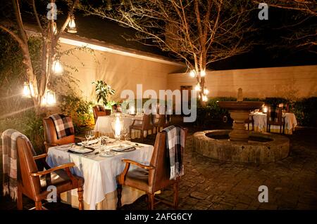 JUN 20, 2011 Serengeti, Tanzanie - Luxe African Safari Lodge restaurant en plein air dans un jardin avec des chaises en cuir tableaux blanc cuisine fine et la guerre Banque D'Images