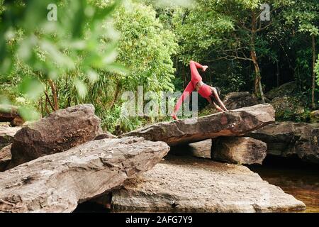 Jolie jeune femme slim faisant une jambe du cobra posent lors de vos entraînements en forêt Banque D'Images