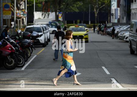 Une femme est en train de parler au téléphone en traversant une rue dans le quartier financier de Singapour. Banque D'Images